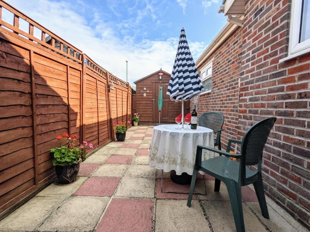 a patio with a table with an umbrella on it at Cullimore, West Wittering in West Wittering