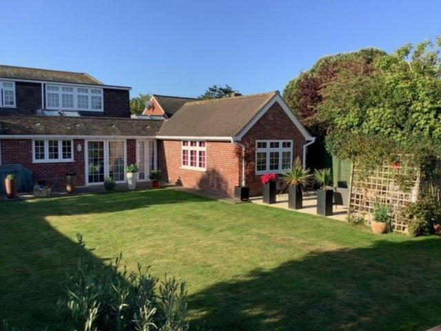 a brick house with a yard with a lawn sidx sidx sidx at Caedwalla House, Selsey in Selsey