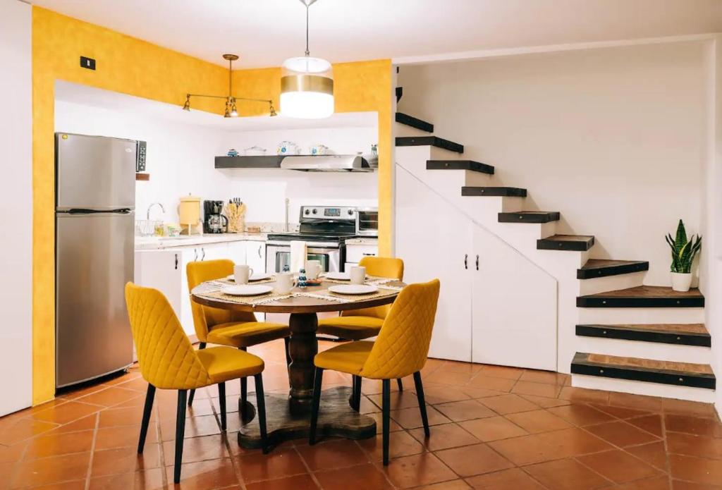 a kitchen and dining room with a table and yellow chairs at Villa Santa Inés in Antigua Guatemala