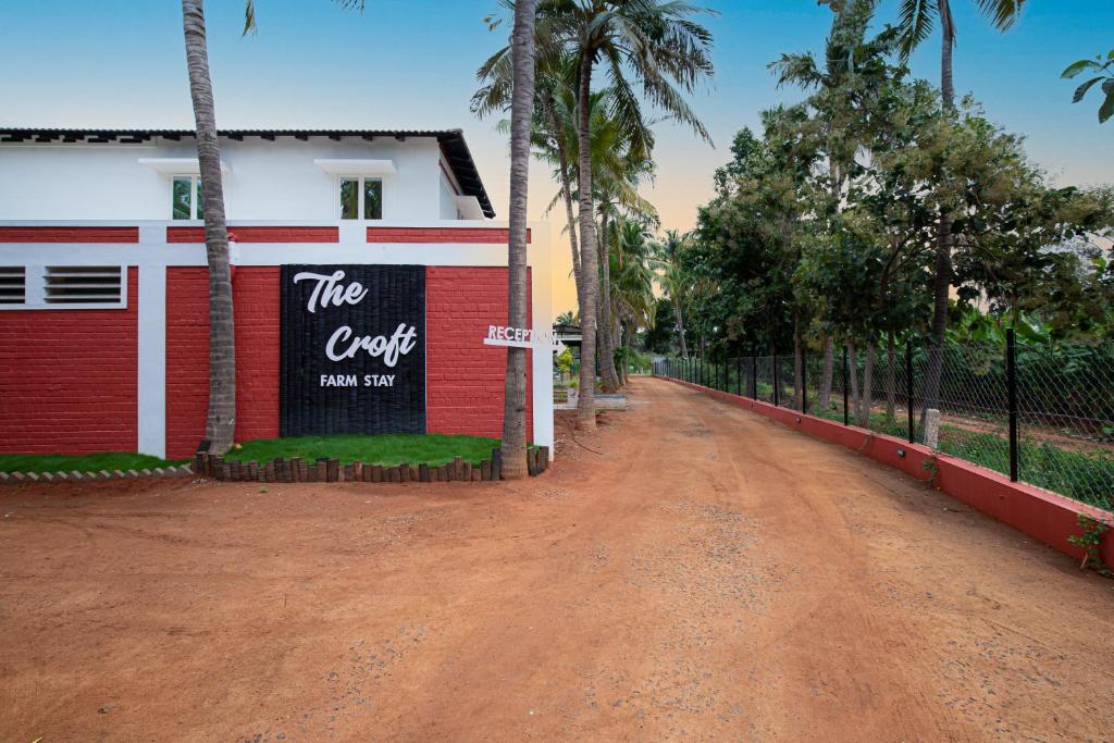 una strada sterrata di fronte a un edificio con un cartello di The Croft Resort - Premium Farm Stay a Tuticorin