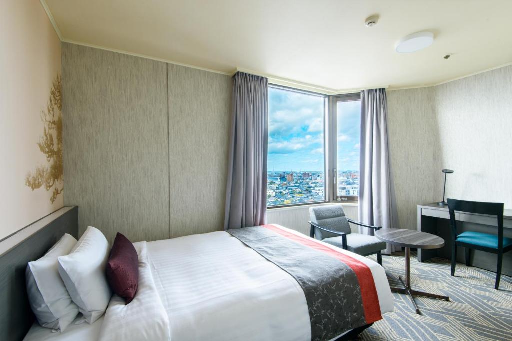 a hotel room with a bed and a desk and a window at Kanazawa Tokyu Hotel in Kanazawa