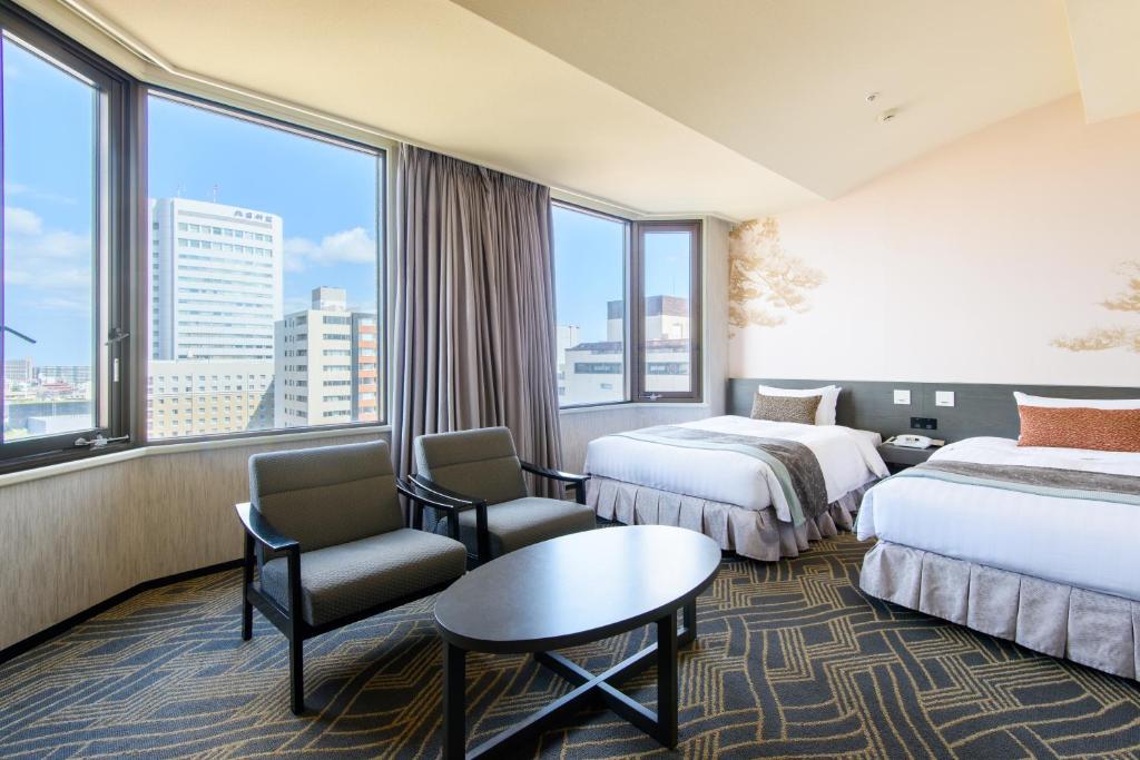 a hotel room with two beds and a table and chairs at Kanazawa Tokyu Hotel in Kanazawa