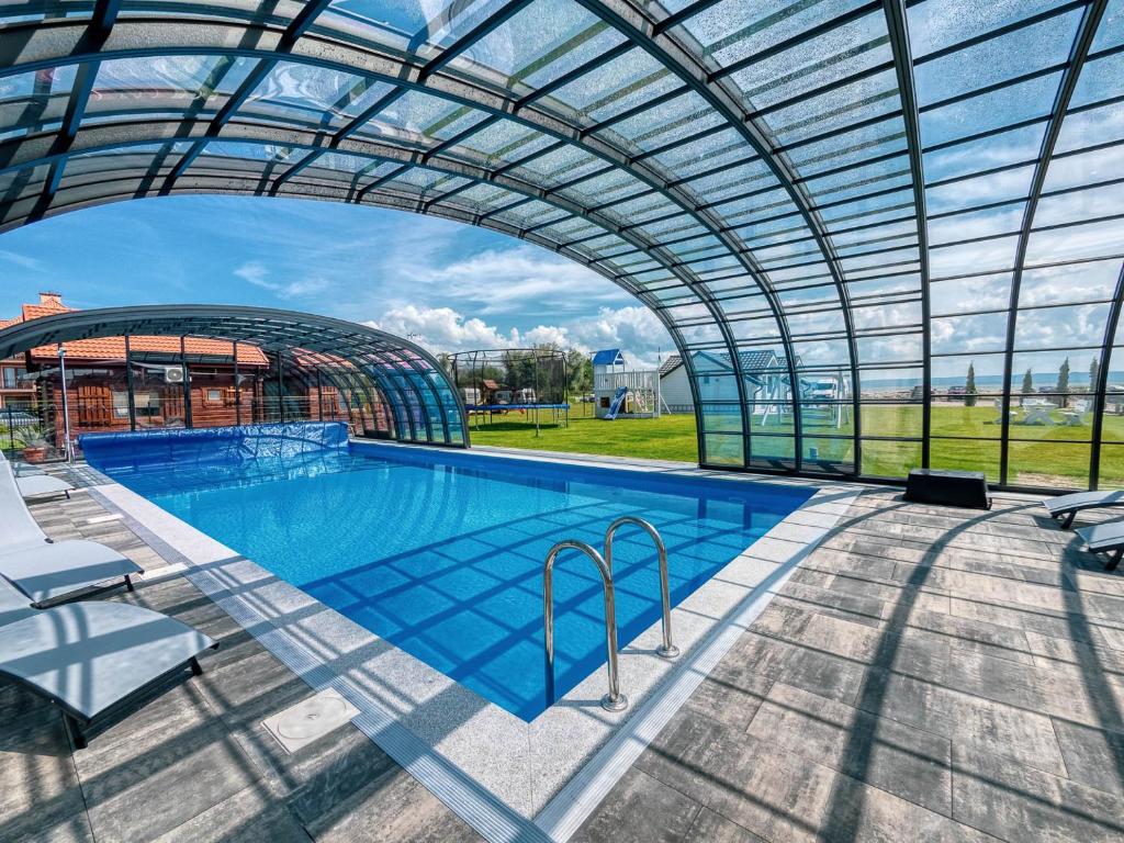 a large swimming pool with a glass domed building at Twój Port in Krynica Morska