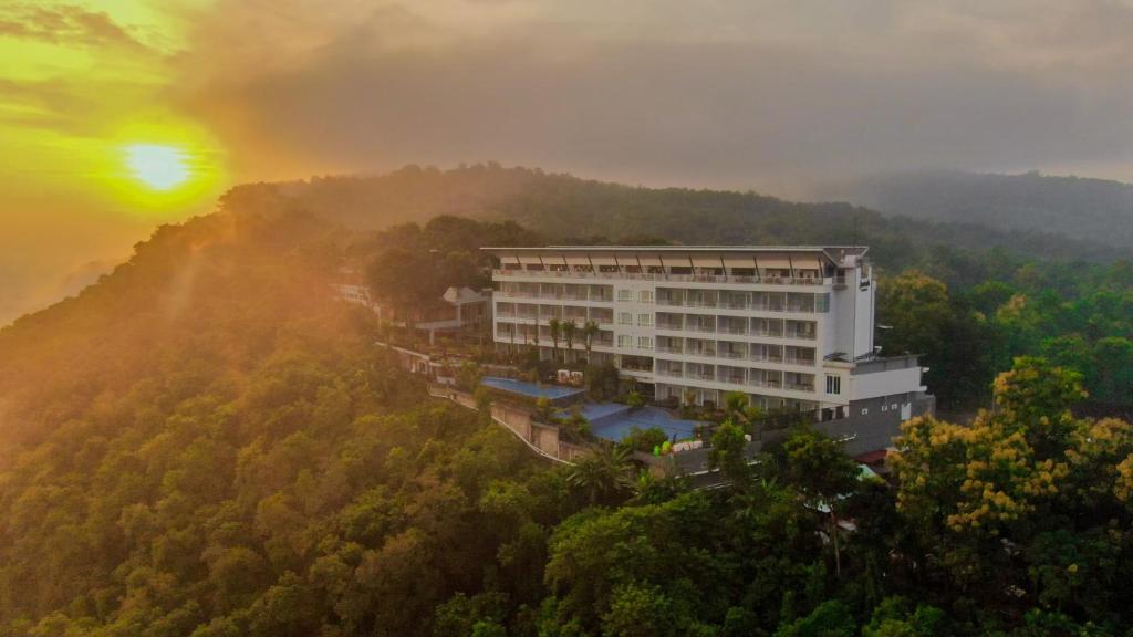 a building in the middle of a forest with the sunset at Amaranta Prambanan Yogyakarta in Yogyakarta