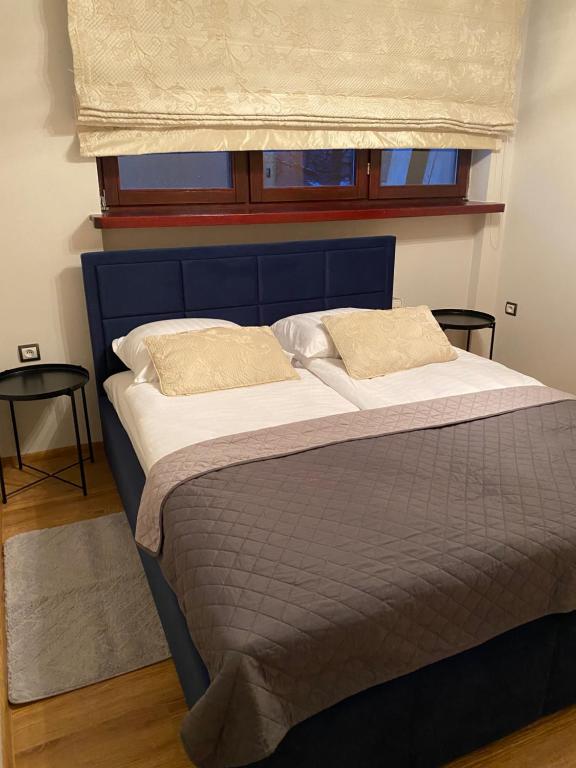 Bett mit blauem Kopfteil und Fenster in der Unterkunft Victoria Aparts Karpacz in Karpacz