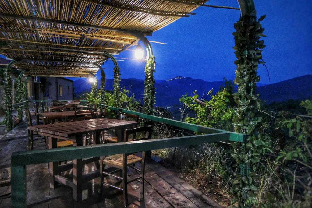 un restaurante con mesas y sillas en un balcón por la noche en Villaggio dei Balocchi, en Castelbuono
