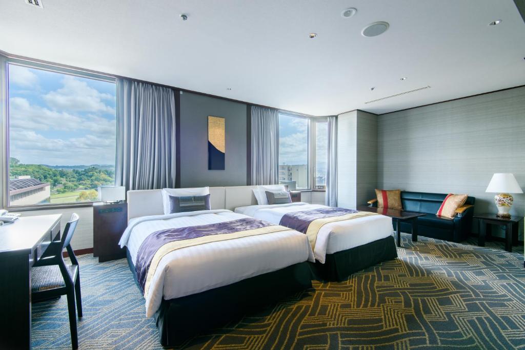 a hotel room with two beds and a desk at Kanazawa Tokyu Hotel in Kanazawa