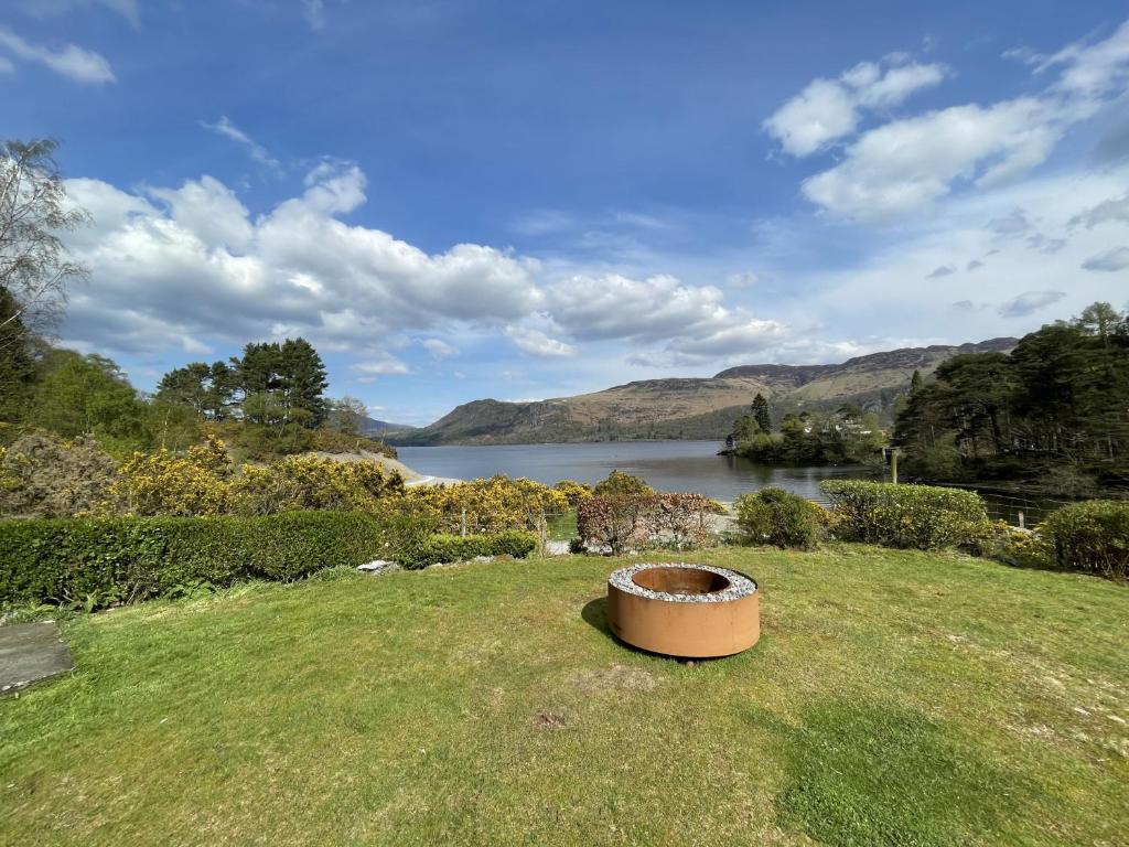 a large pot sitting in the grass next to a lake at Brandlehow in Portinscale