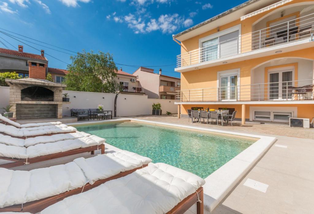 een villa met een zwembad en een huis bij Apartment Jakov with pool in Zadar