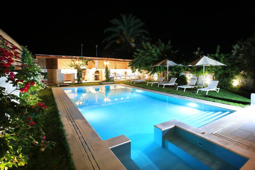 Una piscina de noche con sillas y sombrillas. en Villa Elpida, Kokkini Hani, en Kokkíni Khánion
