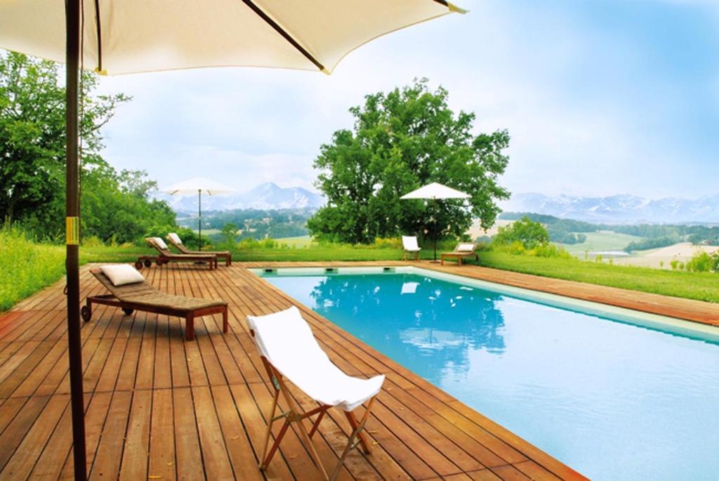 a swimming pool with two chairs and an umbrella at La Maison de Bazugues in Bazugues