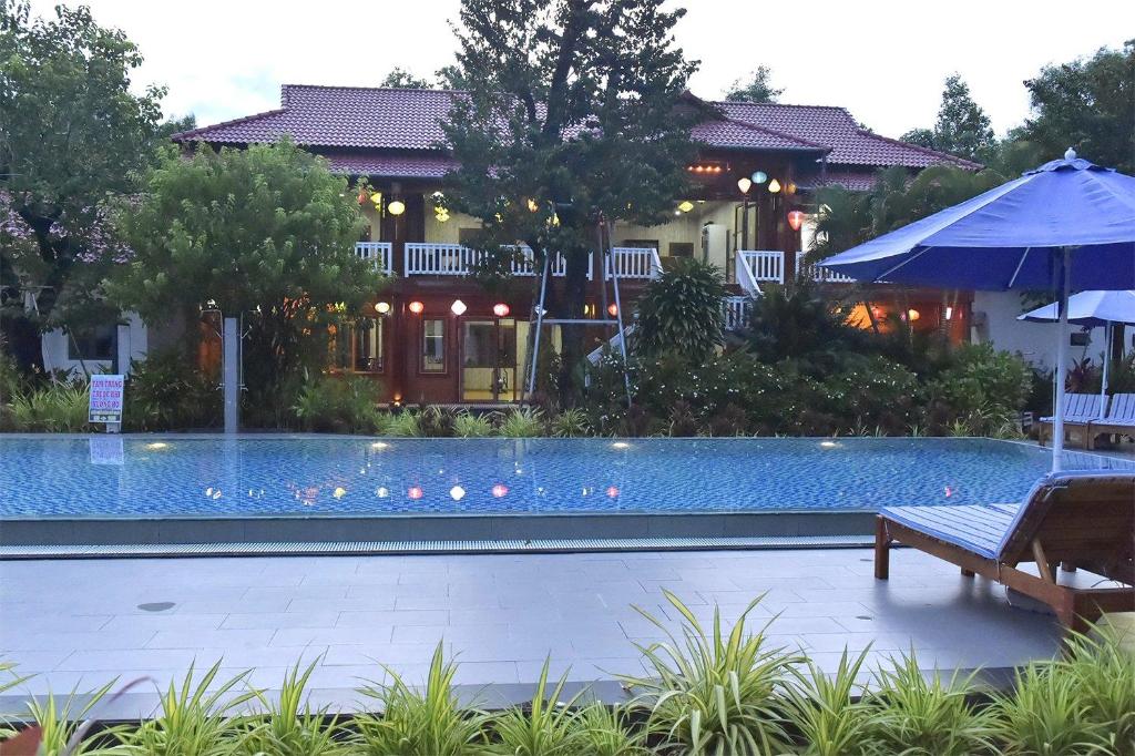 a swimming pool with a bench and an umbrella at Rain Forest Resort Phu Quoc in Phú Quốc