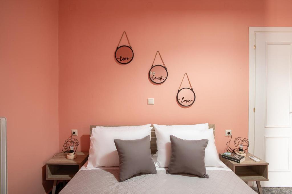 Square Apartment في Kambanós: غرفة نوم بجدران وردية وسرير بمخدات بيضاء