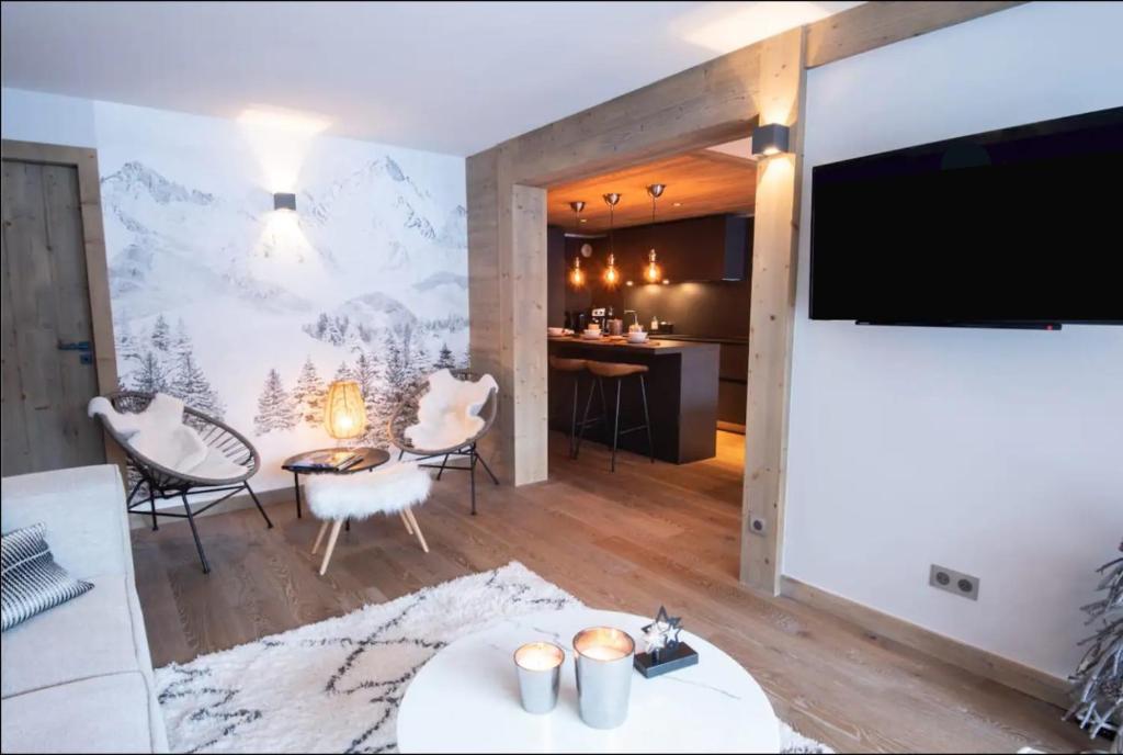 sala de estar con TV de pantalla plana, mesa y sillas en Luxueux appartement skis aux pieds, jacuzzi privatif en Courchevel