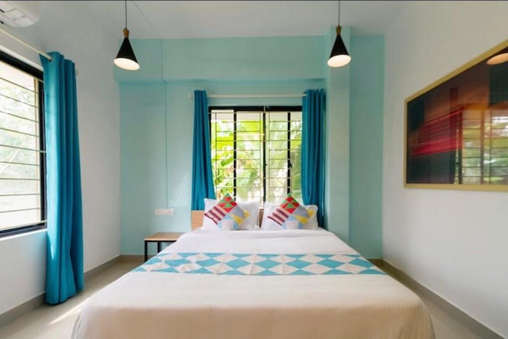 Ecoville suites في كوجيكود: غرفة نوم بسرير والستائر الزرقاء ونافذة