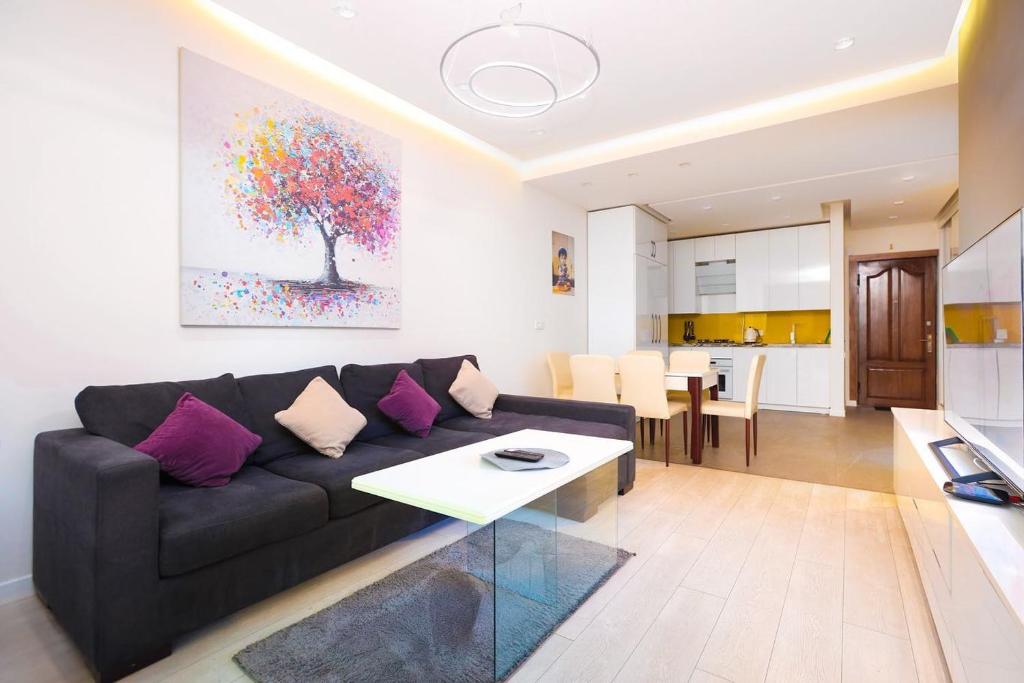 a living room with a black couch and a table at Stay Inn Apartments at Northern Avenue in Yerevan