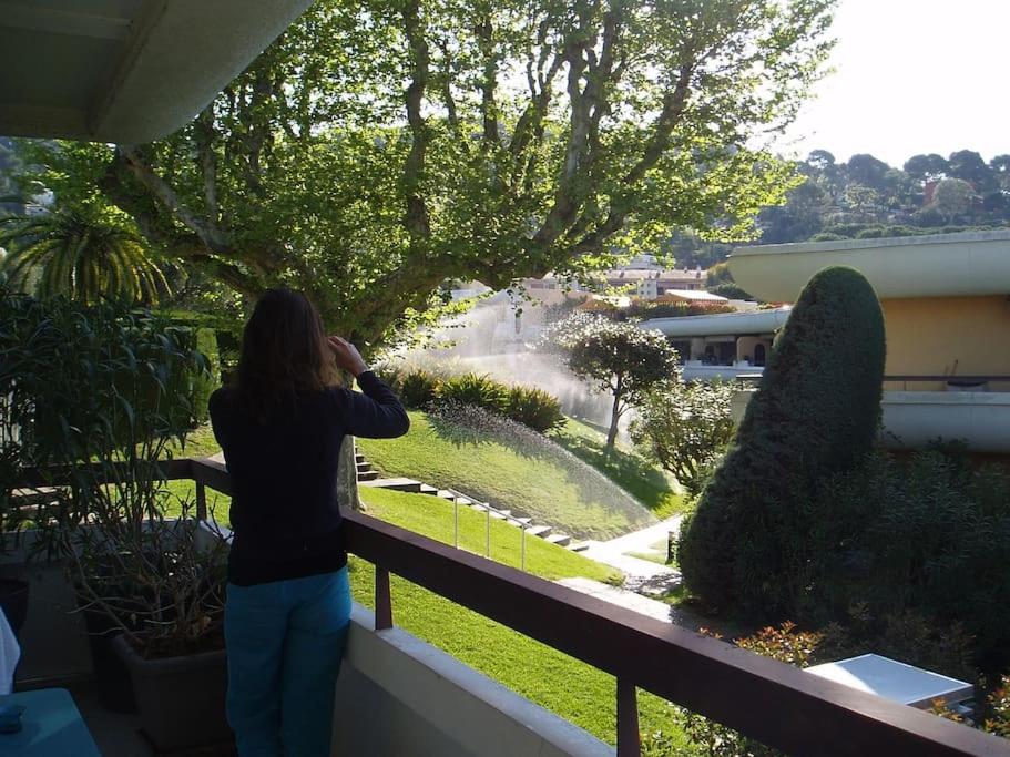 une femme debout sur un balcon donnant sur un jardin dans l'établissement 80m2 dans Parc Classé, Piscine, Calme, 5mn de Cannes, au Cannet
