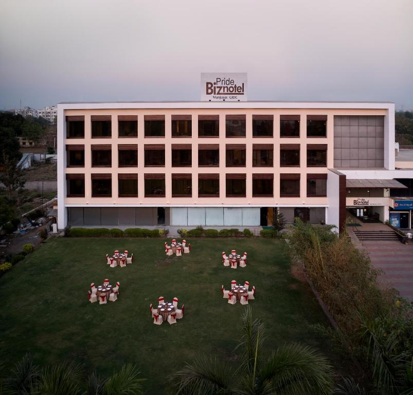 a group of people sitting on a lawn in front of a building at Pride Biznotel Manjusar Vadodara in Vadodara