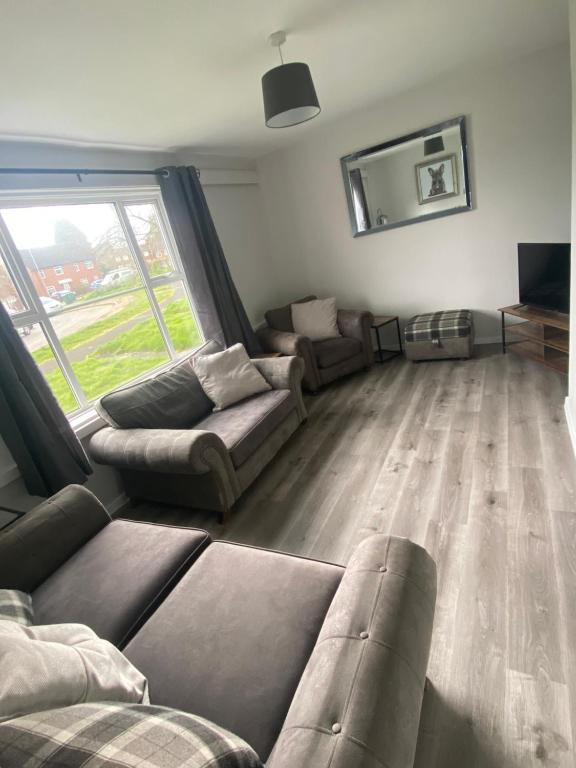 a living room with couches and a large window at Spacious & modern 3 bed house in Stafford