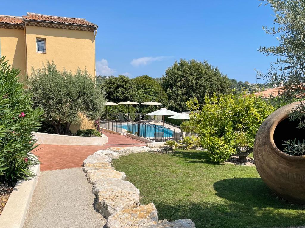 un jardin avec une piscine et un bâtiment dans l'établissement Hotel Marc-Hely, à La Colle-sur-Loup