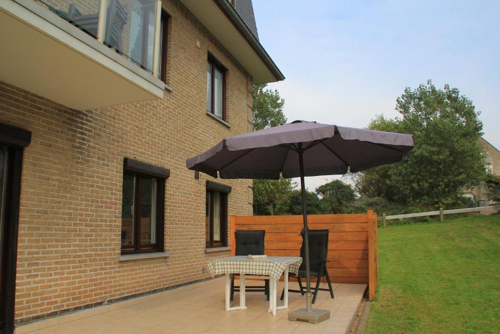 a table and chairs under an umbrella on a patio at Apartment Cuypers in Oostduinkerke