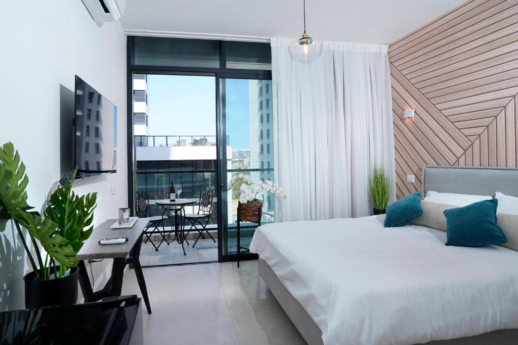 a bedroom with a bed and a balcony with a table at Hi-Yam SeaView Apartments & Suites - Building Shelter Available in Bat Yam