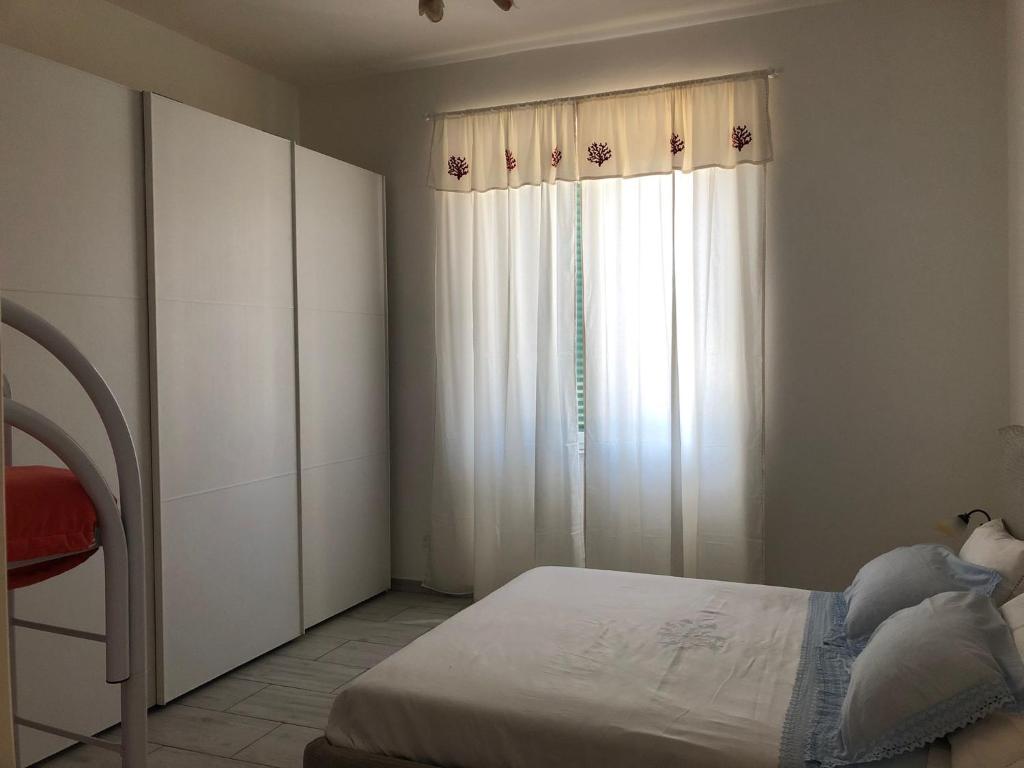 um quarto com uma cama e uma janela com cortinas brancas em casaMare em Venturina Terme