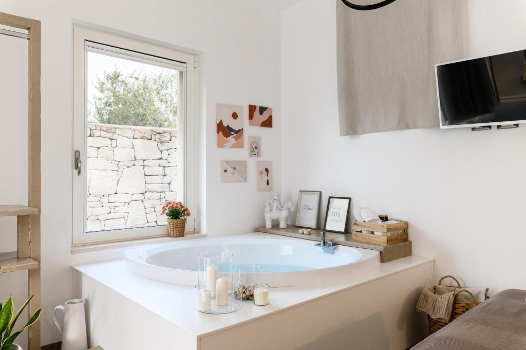 bagno bianco con vasca e finestra di MandorloCarrubo's suite a Ostuni