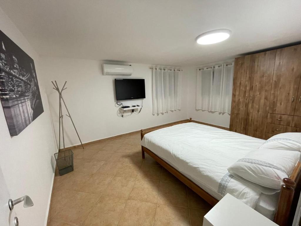 a bedroom with a bed and a flat screen tv at אל מול חרמון- דירה באווירה כפרית עם נוף לחרמון in Sheʼar Yashuv