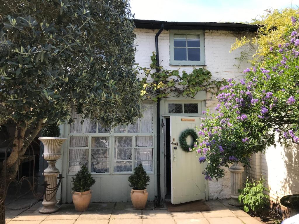 a white house with a door and some flowers at The Clockhouse in Old Windsor