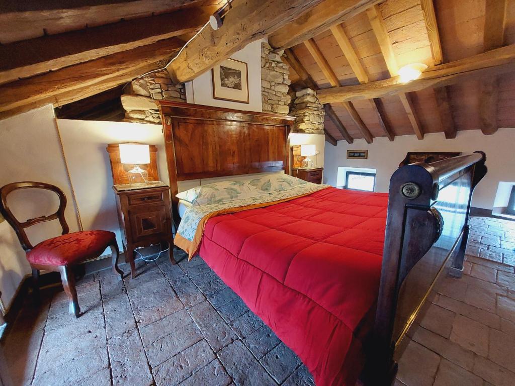 1 dormitorio con 1 cama roja y 1 silla en B&B la Forgia, en Bettola