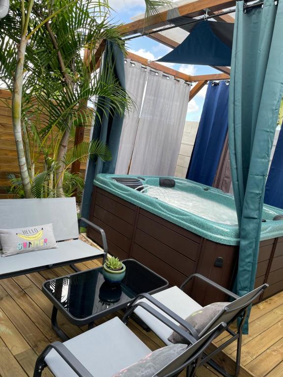 eine Terrasse mit einem Whirlpool, Stühlen und einem Tisch in der Unterkunft Le Coin Trankil in Saint-Louis