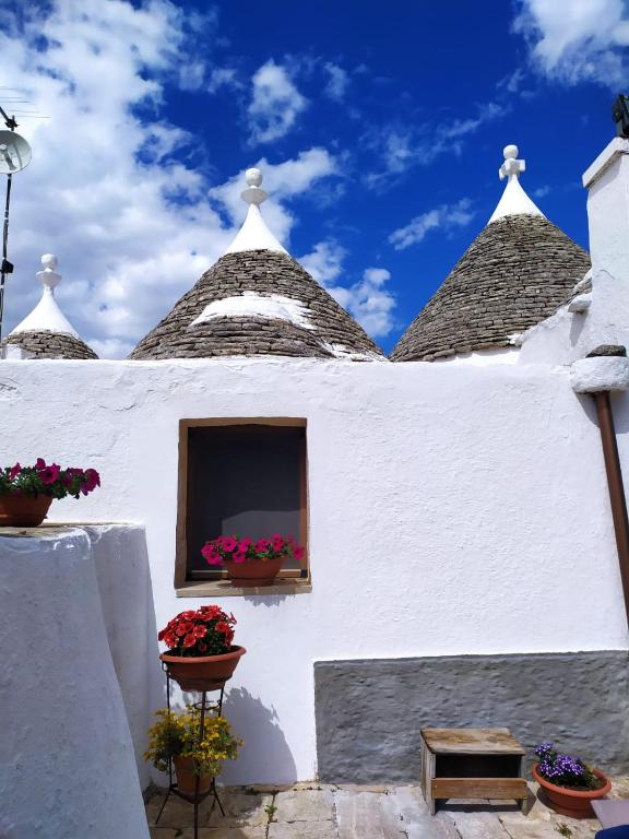 biały budynek z kwiatami w oknie w obiekcie Trulli Demetra w mieście Martina Franca