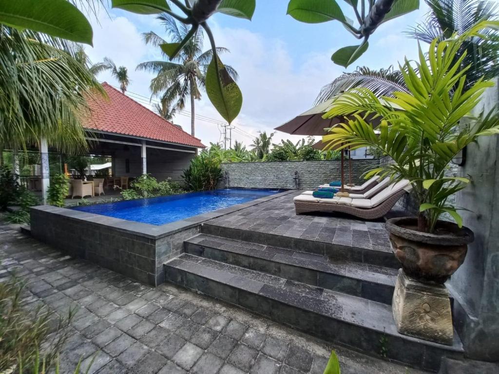 Un patio trasero con piscina y una casa. en Bobo Bungalow, en Nusa Lembongan