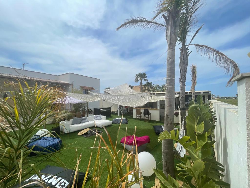 a backyard with a hammock and palm trees at Sunset Wave - STAGNONE KITESURF VILLAGE in Birgi Vecchi