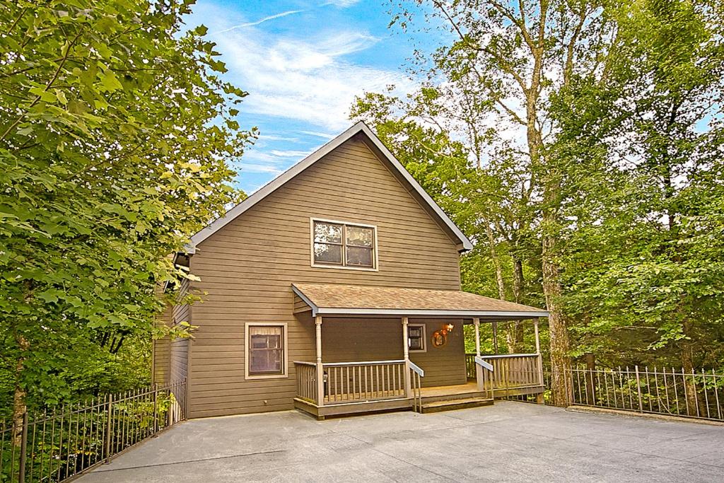 a brown house with a porch and a fence at Sanctuary in Pigeon Forge