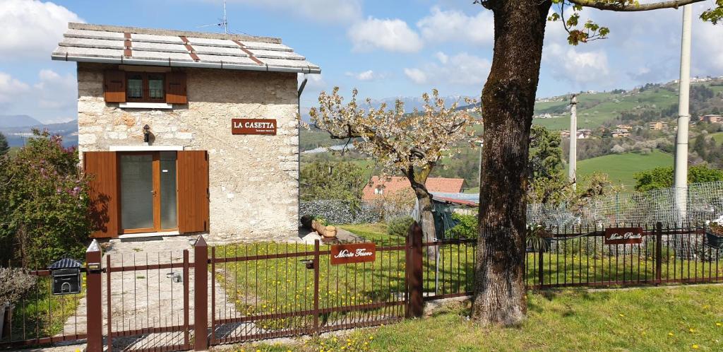 een klein huis met een hek en een boom bij La Casetta in Bosco Chiesanuova