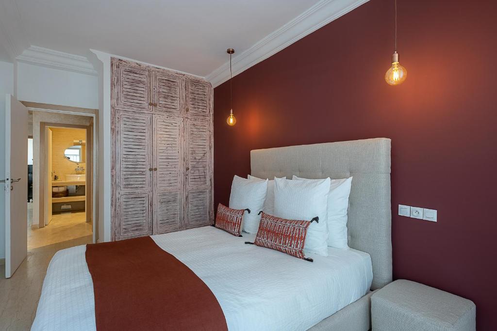 1 dormitorio con 1 cama blanca grande y paredes rojas en Luxury two bedrooms apartment - Best Location, en Rabat