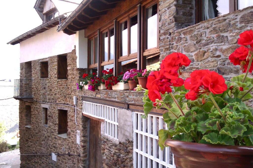 ein Backsteingebäude mit roten Blumen auf einem Zaun in der Unterkunft Casa Rural Jan in Beraní