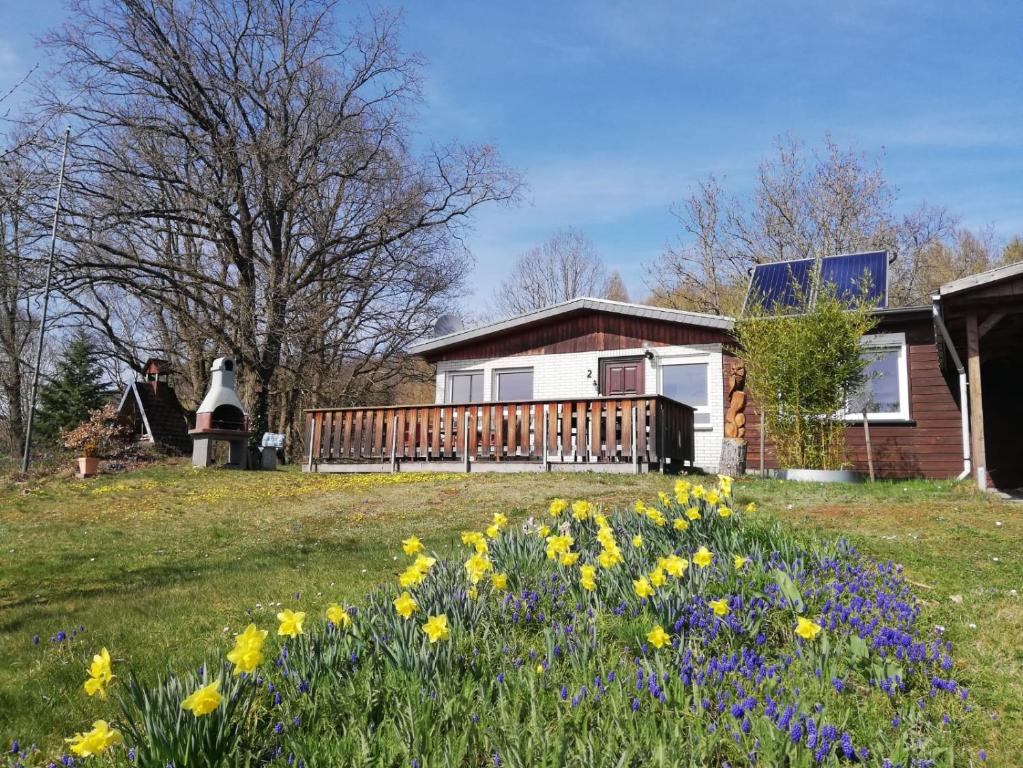 a house with a deck and flowers in the yard at Ferienhaus Chiara, Südharz, Harztor in Ilfeld