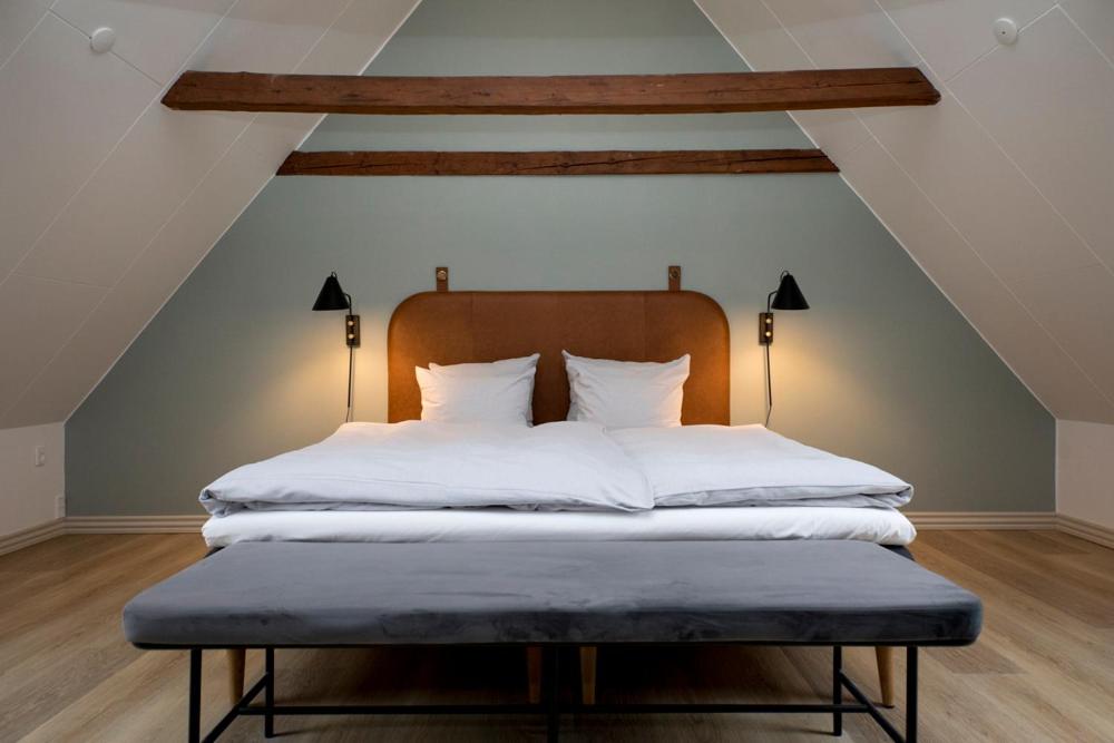 Hotel Løkken Strand في لوكين: سرير ذو أغطية ومخدات بيضاء في العلية
