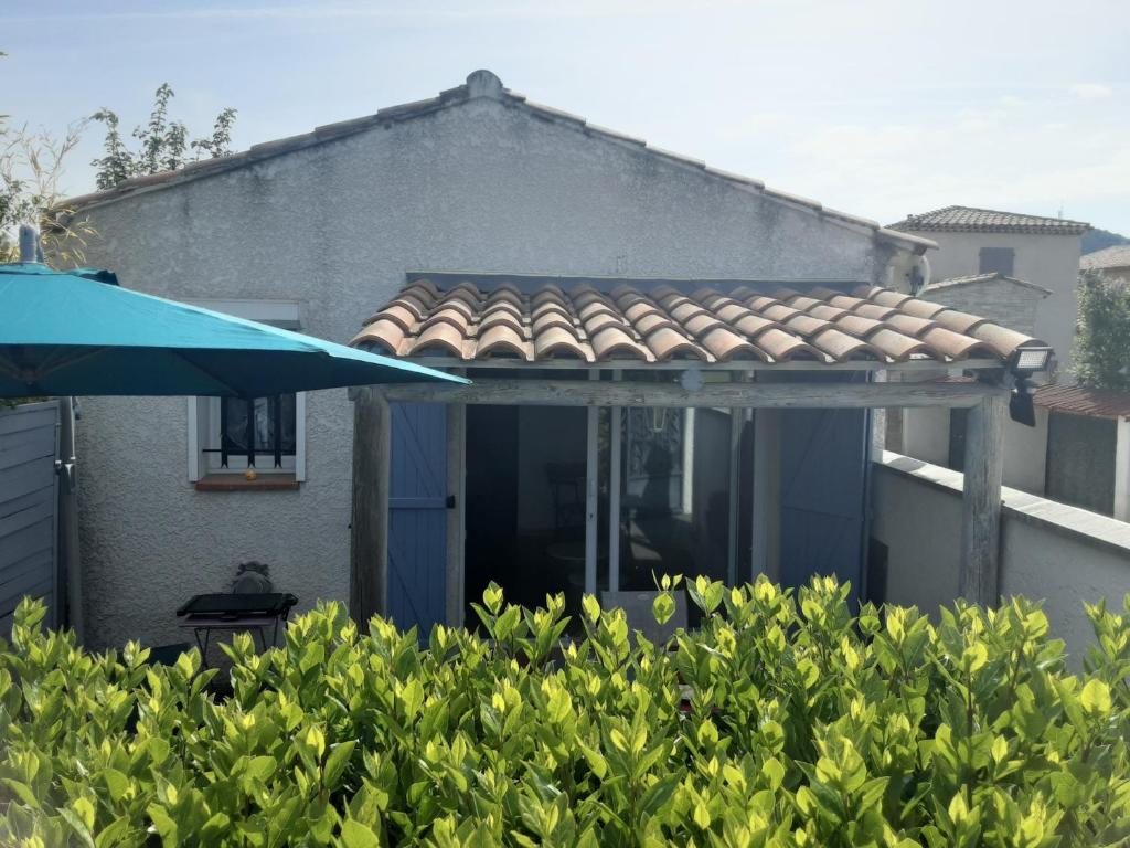 a house with a roof and a blue umbrella at Bord Verdon T2 Maisonnette 35m2 Climatisation - Terrasse 25m2-classé 3étoiles in Gréoux-les-Bains