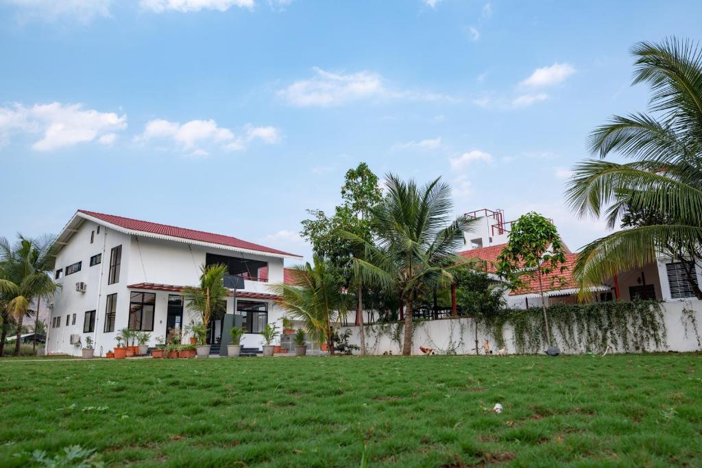 a house with palm trees in front of a yard at The Green Estate Resort in Nashik