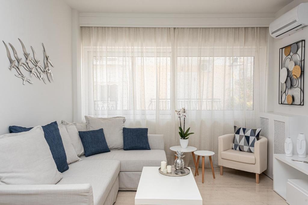 a white living room with a white couch and blue pillows at G&J Deluxe Apt in Zakynthos Town