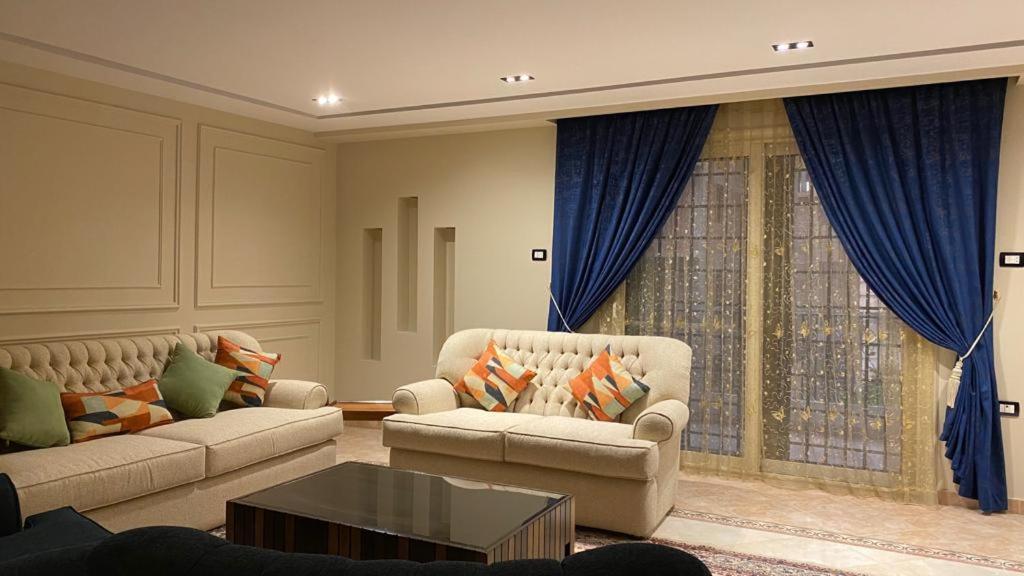 un soggiorno con 2 divani e tende blu di Atallah Hotel Apartments a Città del 6 ottobre