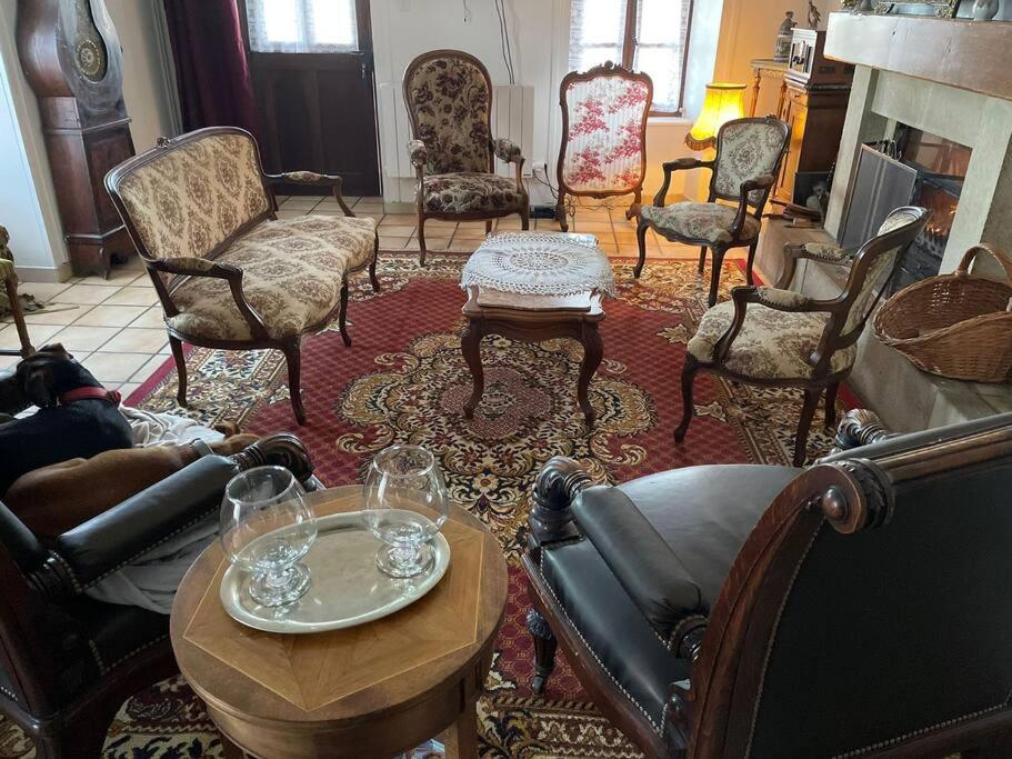 sala de estar con sillas, mesas y chimenea en Maison de campagne chaleureuse et au calme, en Léotoing