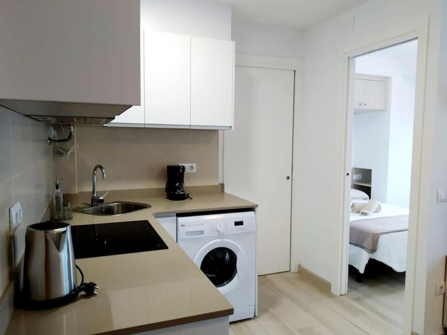 uma cozinha com um lavatório e uma máquina de lavar roupa em Apartament Bonaire em L'Escala