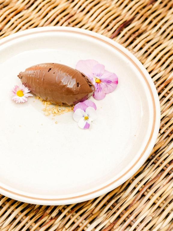 a piece of chocolate on a plate with flowers at Hôtel Restaurant Les Arnelles in Saintes-Maries-de-la-Mer