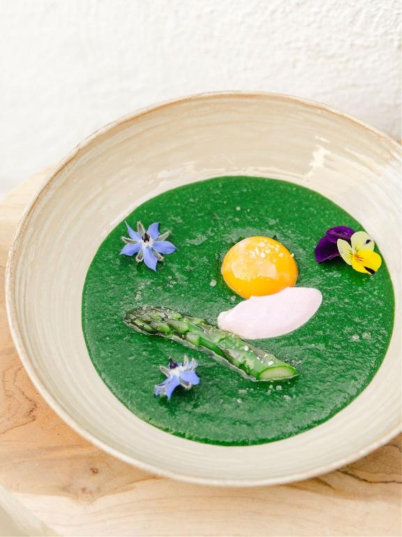 a plate of green sauce with an egg and flowers at Hôtel Restaurant Les Arnelles in Saintes-Maries-de-la-Mer