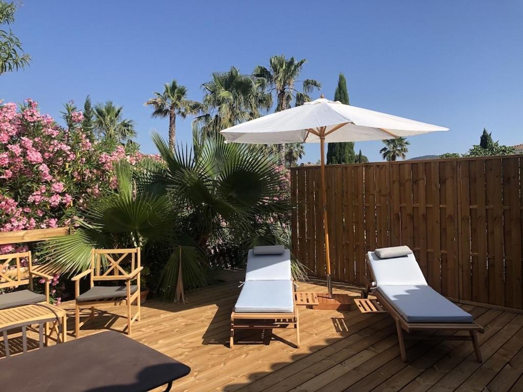 eine Terrasse mit 2 Liegestühlen und einem Sonnenschirm in der Unterkunft Green village in Roquebrune-sur-Argens